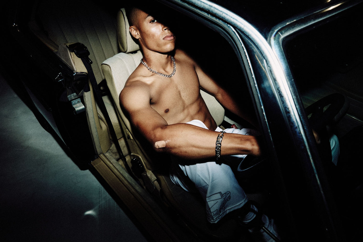 topless male model in sweatpants in the front seat of a car