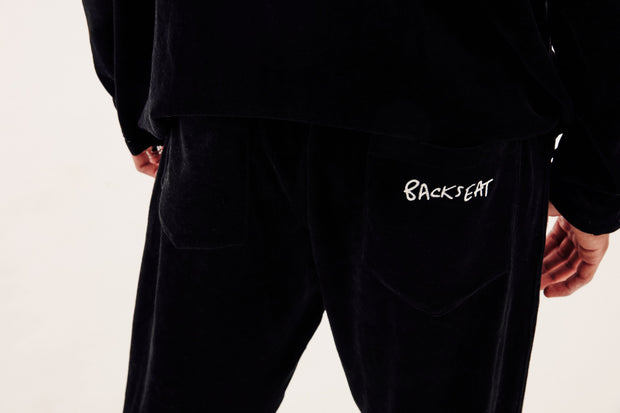 close up of backseat kissing logo on the back of black velour tracksuit bottoms