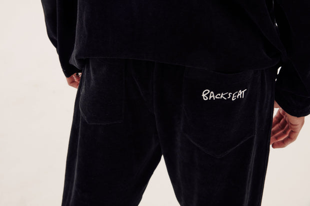 close up of backseat kissing logo embroidered onto back pocket of velour tracksuit bottoms