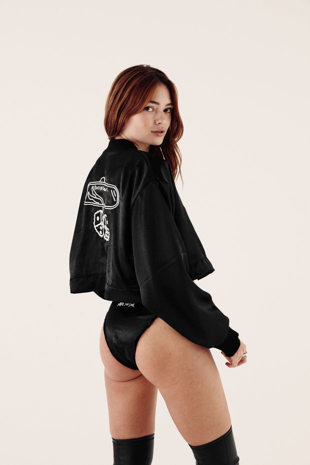 female model looking over her shoulder wearing satin bomber jacket and satin knickers
