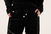 close up of embroidery on black velour tracksuit bottoms