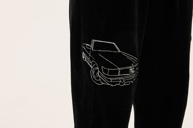 close up of embroidery on black velour tracksuit bottoms
